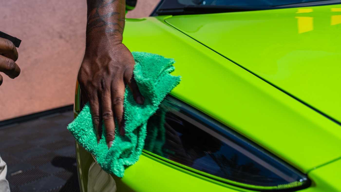 Detailer carefully wiping the front corner of a vehicle