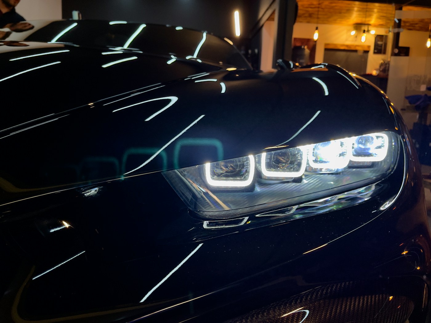 Bright modern headlight on a glossy black car